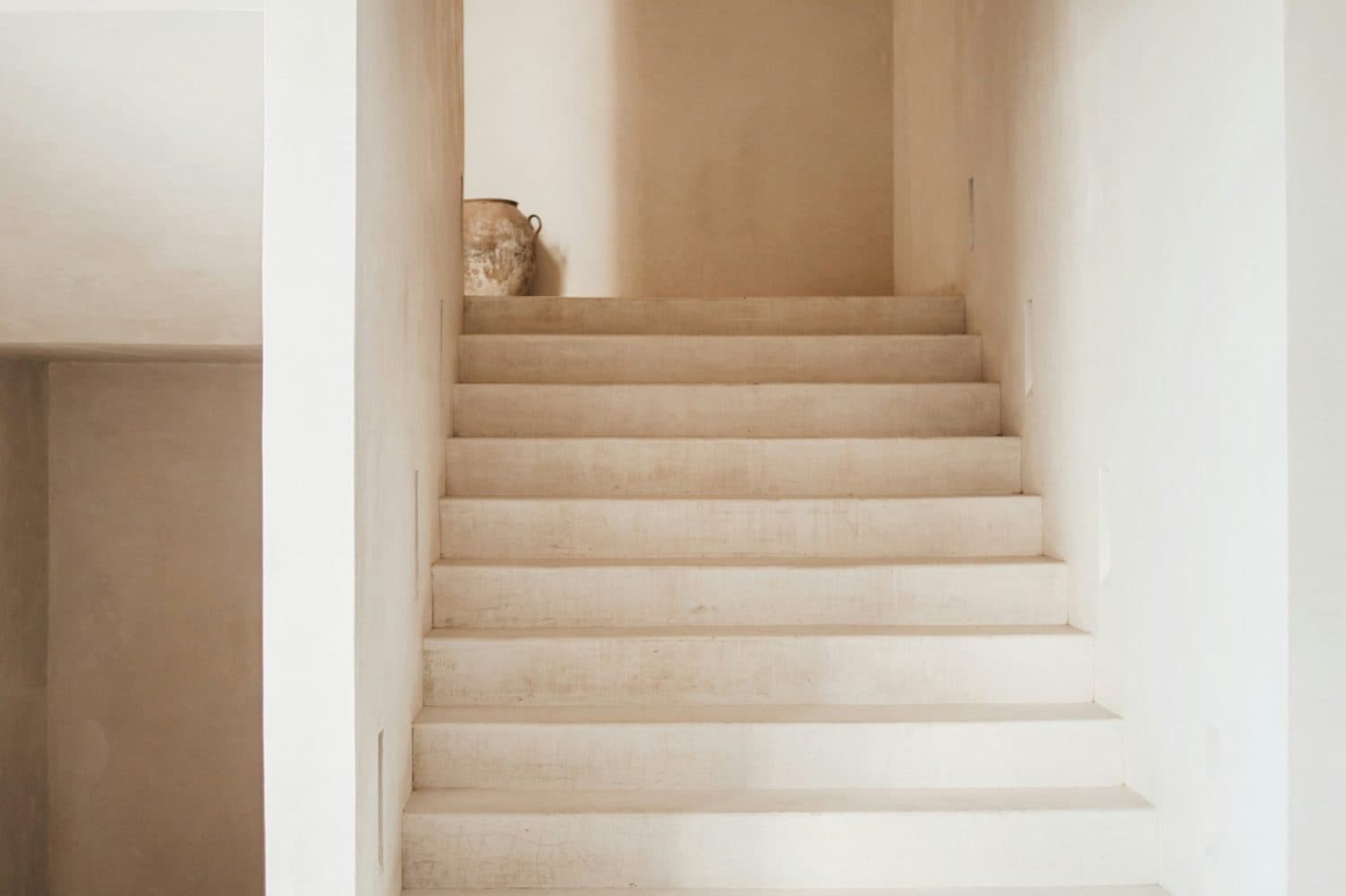 A plaster staircase in a quiet, light filled hall