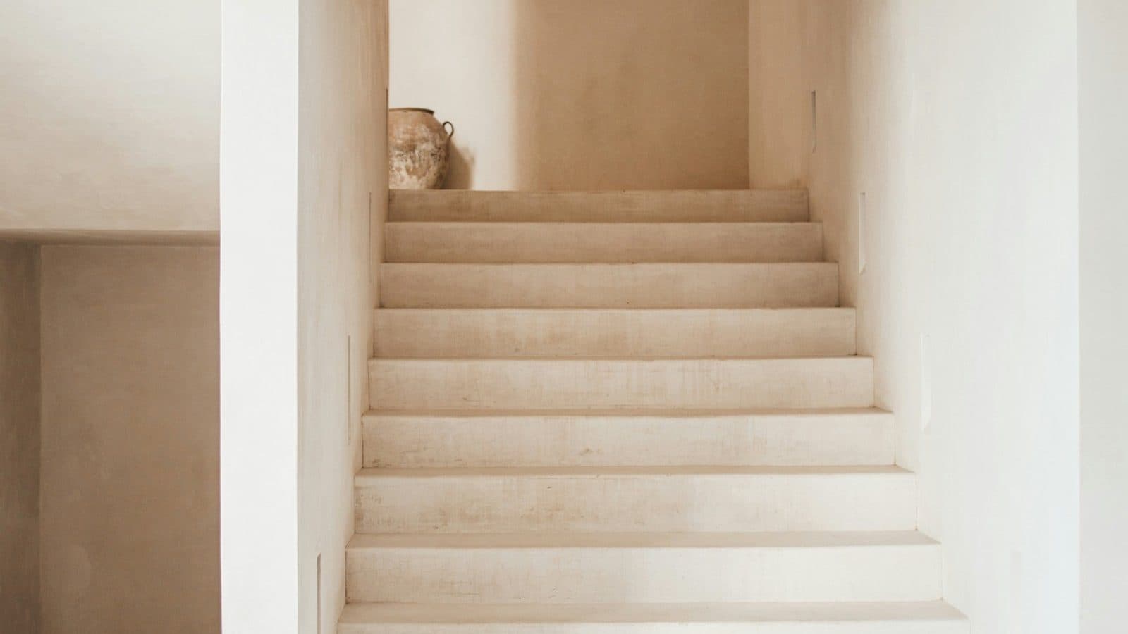 A plaster staircase in a quiet, light filled hall